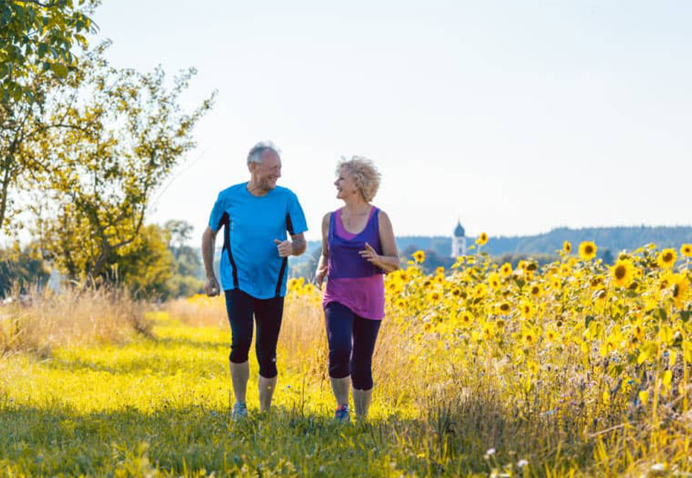 couple-jogging-by-a-sunflower-field-discussing-a-deferred-annuity-social